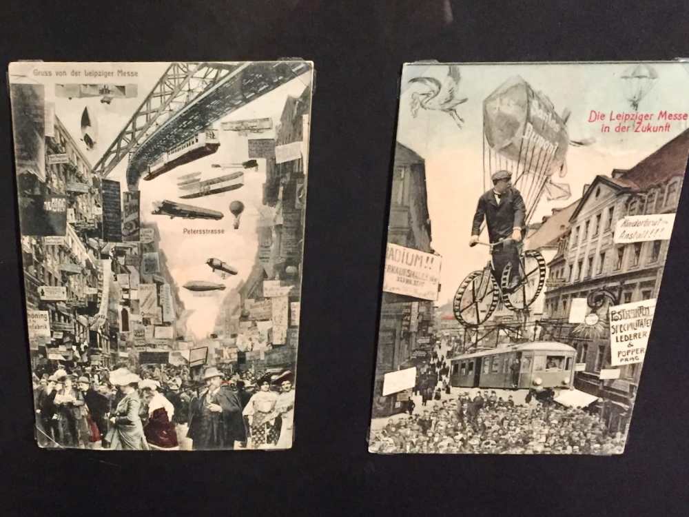 Two vintage German postcards show busy city streets with crowds, billboards, railways, and flying machines; captions reference the Leipzig trade fair and its imagined future.
