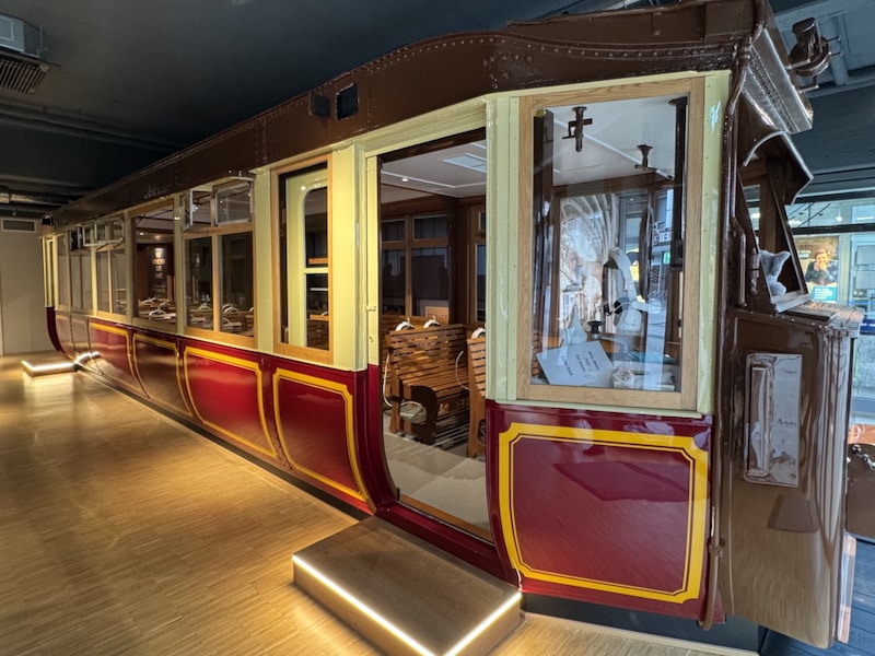 Historic red suspension railway wagon with wooden seats and white VR headsets; photo from the Schwebodrom Museum in Wuppertal.